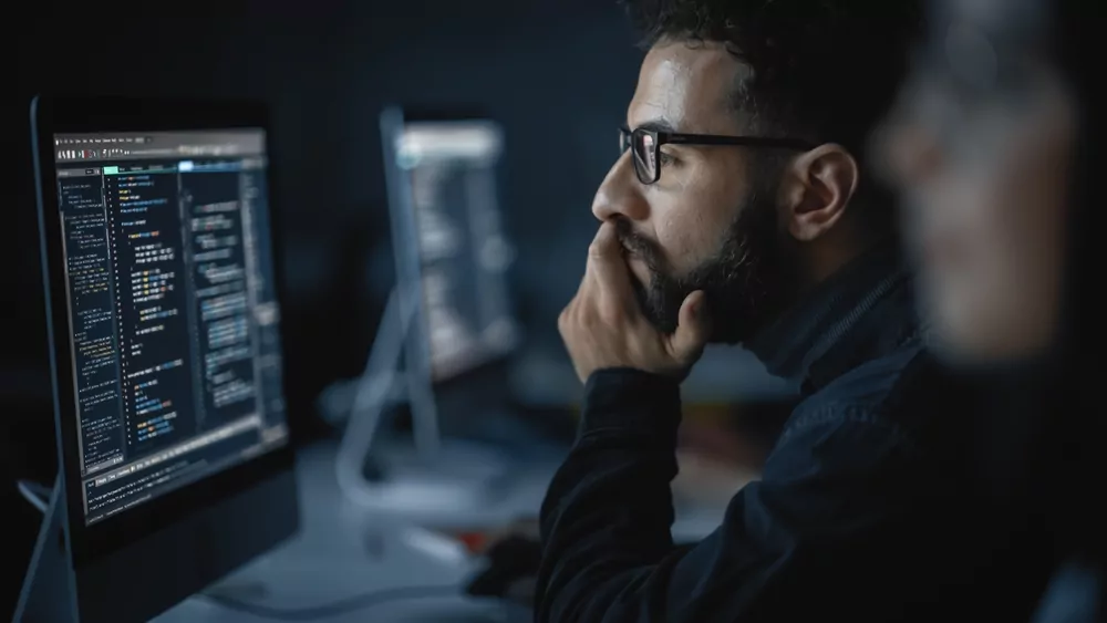 man looking at sports tech on computer in the dark